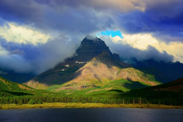 Montanhas entre as nuvens na margem do lago