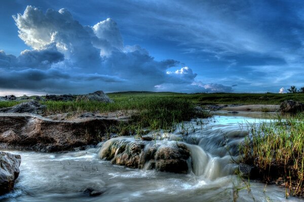 Wasserströme, die über die Steine auf dem Hintergrund des bewölkten Himmels laufen