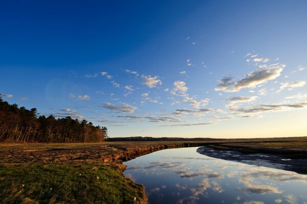 El río pasa entre los campos y el cielo reflectante