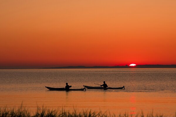 Les gens nagent sur des bateaux pendant le coucher du soleil