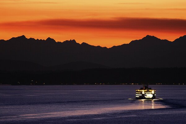 Motorschiff im Nachtfluss vor dem Hintergrund der dunklen Berge