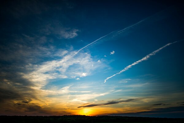 The trail of a flying plane at sunset