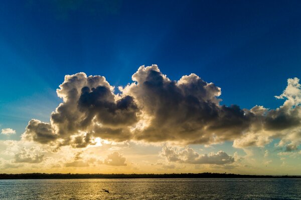 Die Sonne hinter den Wolken am Wasser