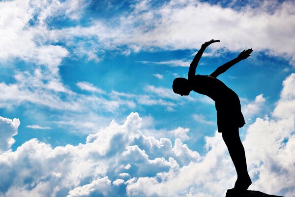 A man jumps from a springboard against the background of clouds