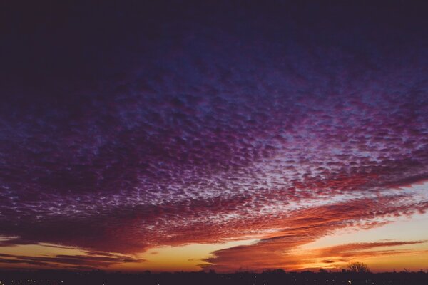 Bröckelige violette Wolken über den ganzen Himmel, die rot-orange verfärben