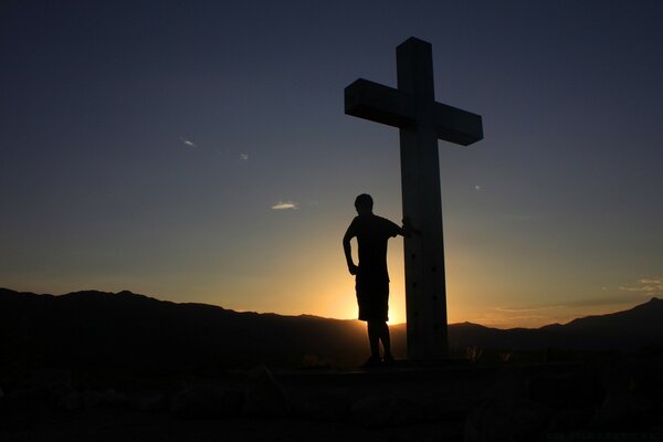 Silhouette of a man on the background of a cross