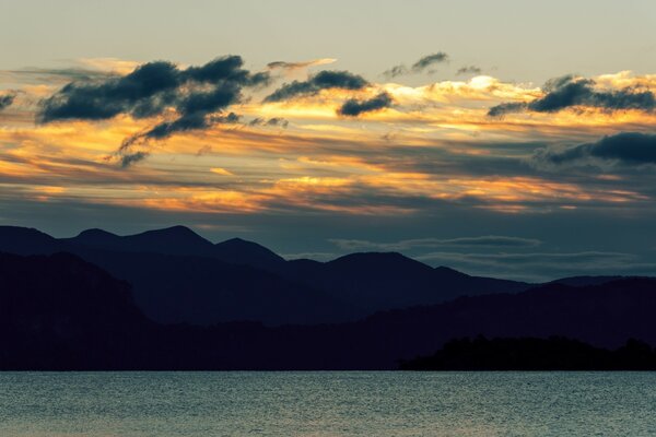 Sunset over the water on the background of mountains