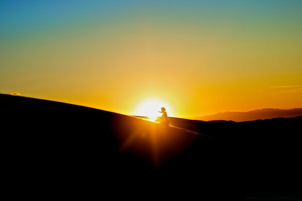 A girl against the background of dawn climbs a hill