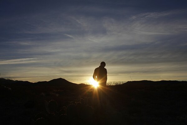 Hombre de pie en el fondo de la puesta de sol