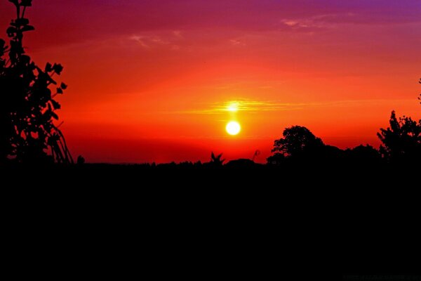 Sonnenuntergang vor dem Hintergrund des feurig-orangefarbenen Himmels