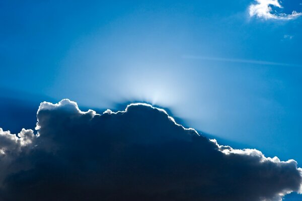 The sun behind the cloud in the blue sky