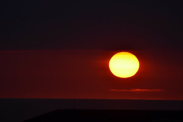 The setting sun on the background of a crimson sky