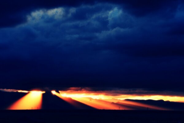 Ein Sonnenuntergang Himmel mit Wolken, durch den die Sonnenstrahlen ihren Weg finden