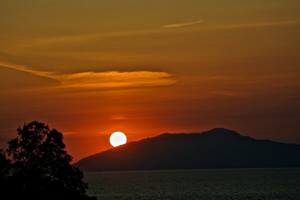 The sun sets behind the mountain at sunset