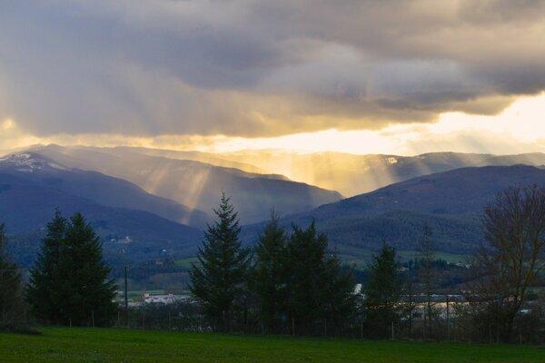 Die Sonnenstrahlen brechen durch die Wolken über den Bergen