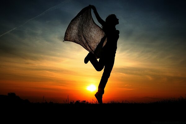 Silueta de una chica flotando al atardecer