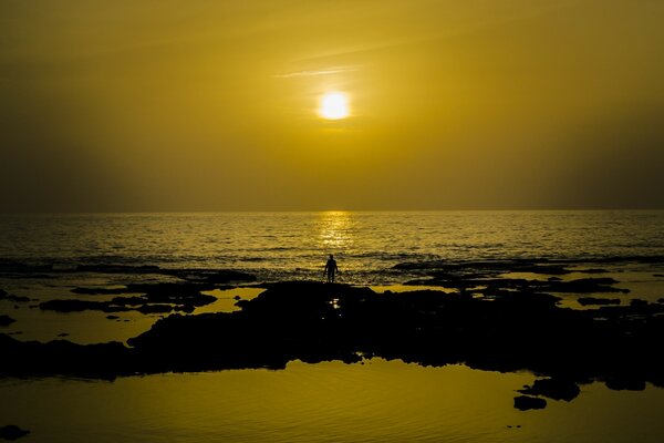 Ein Mann am Wasser schaut auf den Sonnenuntergang