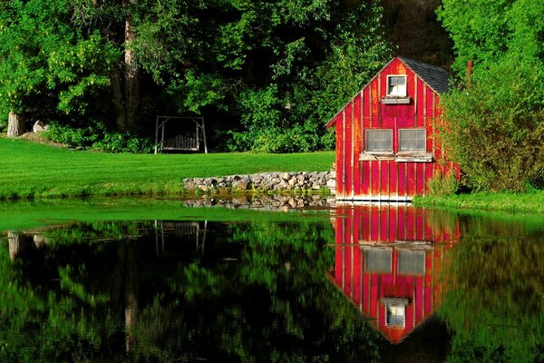 Красный дом с качелью на берегу озера