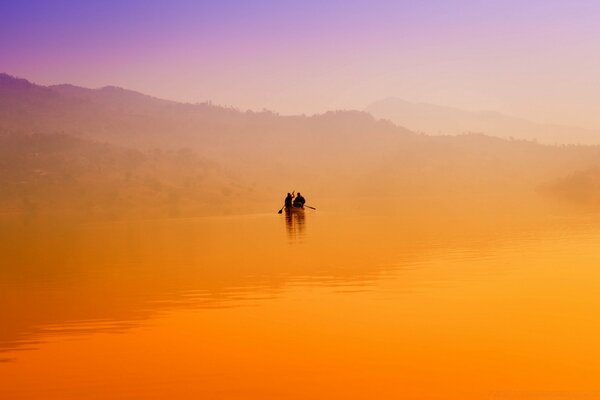 Barco com pessoas no pôr do sol laranja