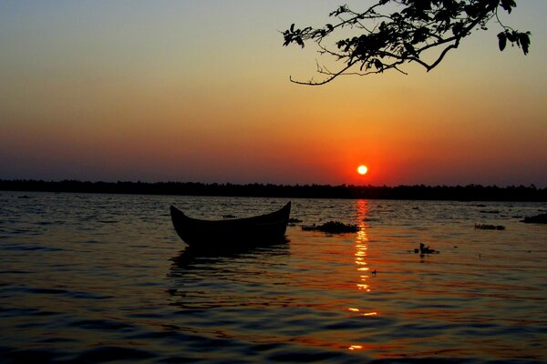 Boot im Wasser auf dem Hintergrund des roten Sonnenuntergangs