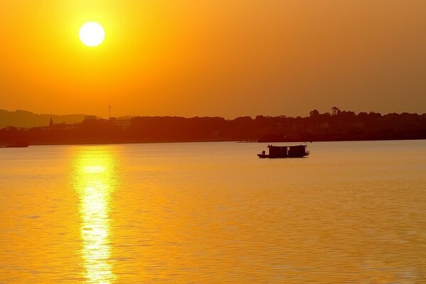 Das Boot fährt in den Sonnenuntergang entlang der Stadt