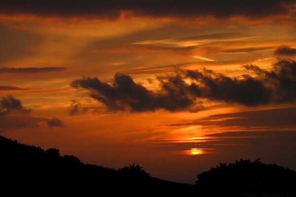 O pôr do sol coberto por nuvens escuras