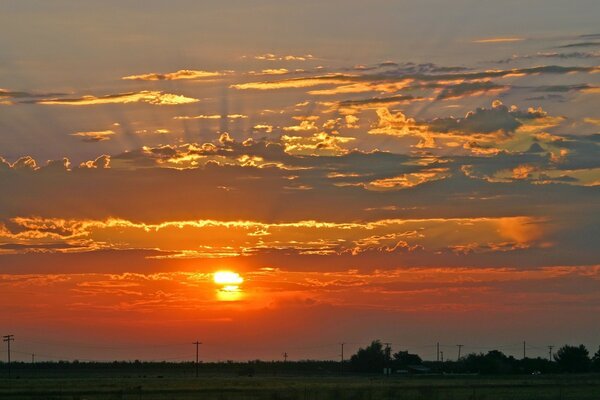 The sun at dawn on the background of a power line