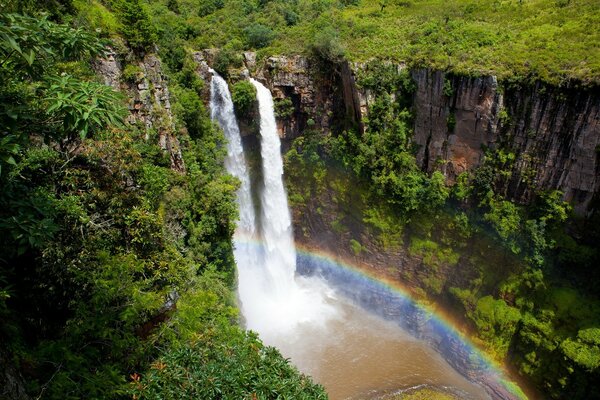 Wasserfall und leichter Regen. Regenbogen-Bogen