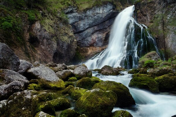 The waterfall flows into the turbulent flow of the river