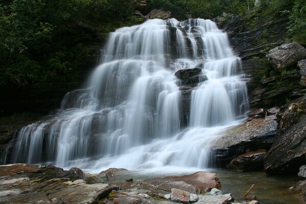 A strong waterfall on the rocks by the river