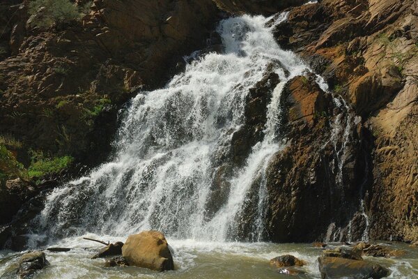 Wasserfall in der Nähe eines felsigen Hügels