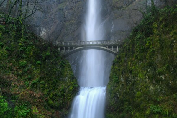 Une grande et puissante cascade descend dans la rivière à travers un pont