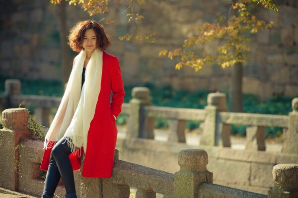 The girl is sitting leaning on the fence