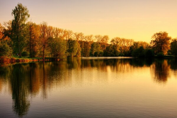 Meeting the dawn by the lake against the background of the autumn forest