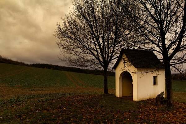 Autumn landscape a barn between trees under a cloudy sky