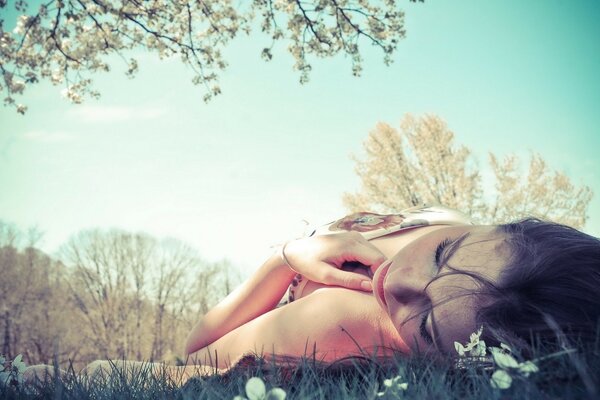 The girl is lying on the grass during the day