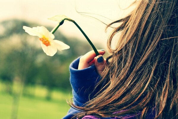 Una niña sostiene una flor en la mano