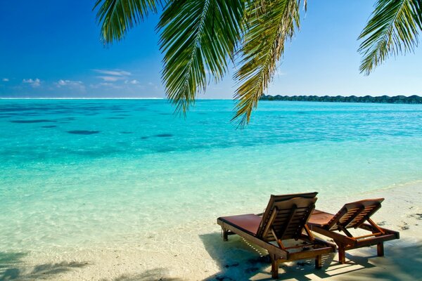 Strand mit blauem Wasser und Liegestuhl