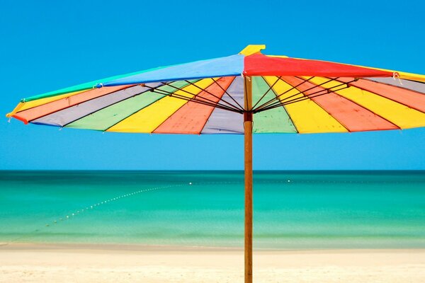 Parapluie arc-en-ciel sur la plage dans la mer