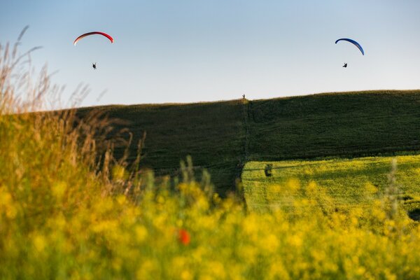 Two parachutists are planning in the air