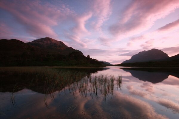 Pink sunset. Pink clouds over the lake. Mountains. Twilight