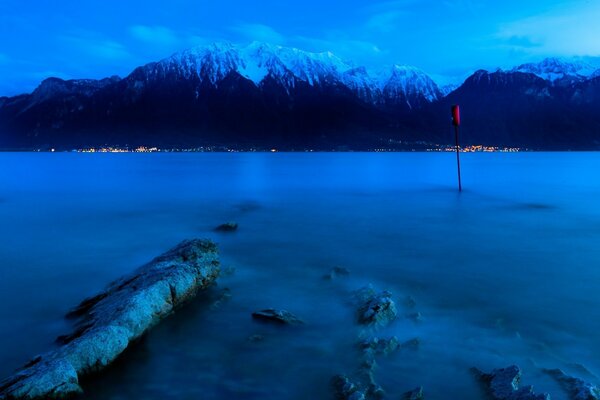 Twilight on the lake. Mountain peaks in the snow