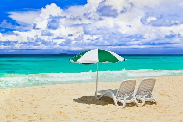 Liegestühle und Sonnenschirm am Sandstrand