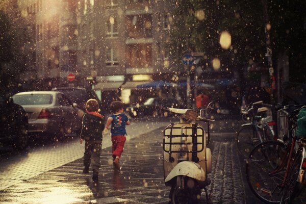 Bambini che corrono sotto la calda pioggia primaverile