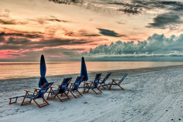 Liegestühle am Sandstrand bei Sonnenuntergang