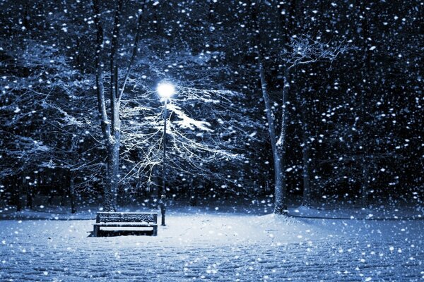 Schneesturm im Park an der Bank mit Laterne