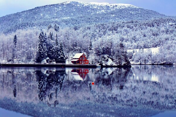 Maison au bord du lac sur fond de paysage d hiver et de la montagne