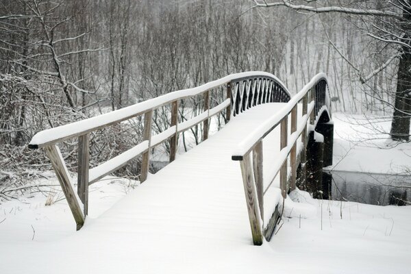 Puente cubierto de nieve sobre un pequeño río