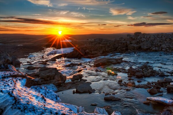 Sonnenuntergang über einer Winterlandschaft mit Steinen