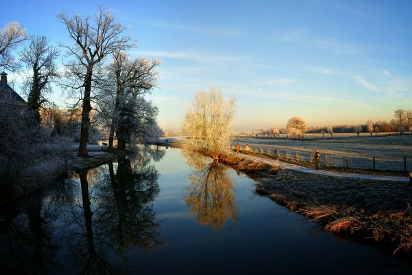 Bäume im Schatten und in der Sonne spiegeln sich im Fluss wider